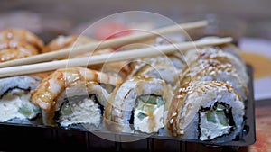 Japanese Sushi Rolls in Plastic Box are Served on Table with Bamboo Sticks. Zoom