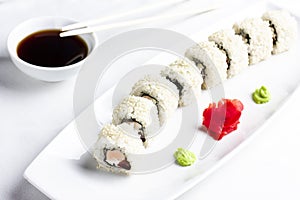 Japanese sushi rolls with salmon in rice and sesame on white plate