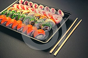 Japanese sushi rolls in the shape of a line on black background top view