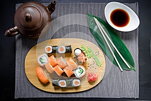 Japanese sushi rolls, soy sauce, ginger and chopsticks on dark background. Top view. Flat lay.