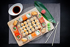 Japanese sushi rolls, soy sauce, ginger and chopsticks on a dark table. Top view. Flat lay. Japanese traditional food