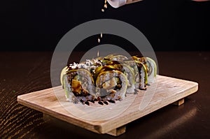 Japanese sushi rolls in the Ukrainian seafood restaurant. Sushi with tuna and avocado sprinkled with sesame. Rolls on a wooden