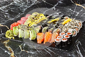 Japanese sushi set. Set of fresh tuna maki , salmon nigiri and dragon sushi rolls served on black plate close-up. Horizontal top