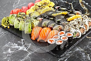 Japanese sushi set. Set of fresh tuna maki , salmon nigiri and dragon sushi rolls served on black plate close-up. Horizontal top