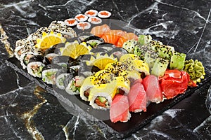 Japanese sushi set. Set of fresh tuna maki , salmon nigiri and dragon sushi rolls served on black plate close-up. Horizontal top