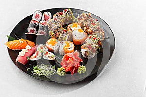 Japanese sushi set. Set of fresh tuna maki , salmon nigiri and dragon sushi rolls served on black plate close-up. Horizontal top