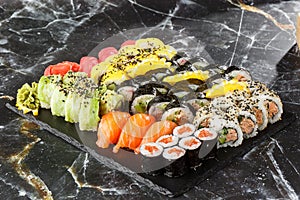 Japanese sushi set. Set of fresh tuna maki , salmon nigiri and dragon sushi rolls served on black plate close-up. Horizontal top