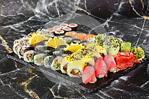 Japanese sushi set. Set of fresh tuna maki , salmon nigiri and dragon sushi rolls served on black plate close-up. Horizontal top