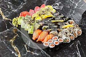 Japanese sushi set. Set of fresh tuna maki , salmon nigiri and dragon sushi rolls served on black plate close-up. Horizontal top
