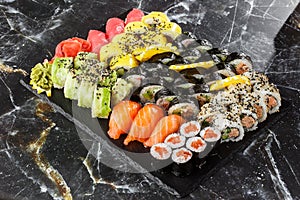 Japanese sushi set. Set of fresh tuna maki , salmon nigiri and dragon sushi rolls served on black plate close-up. Horizontal top