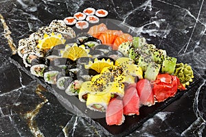 Japanese sushi set. Set of fresh tuna maki , salmon nigiri and dragon sushi rolls served on black plate close-up. Horizontal top