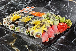 Japanese sushi set. Set of fresh tuna maki , salmon nigiri and dragon sushi rolls served on black plate close-up. Horizontal top