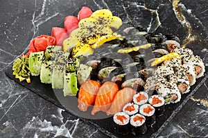 Japanese sushi set. Set of fresh tuna maki , salmon nigiri and dragon sushi rolls served on black plate close-up. Horizontal top