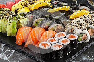 Japanese sushi set. Set of fresh tuna maki , salmon nigiri and dragon sushi rolls served on black plate close-up. Horizontal top