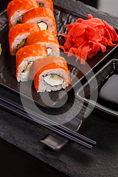 Japanese sushi with soy sauce and chopsticks on black background.