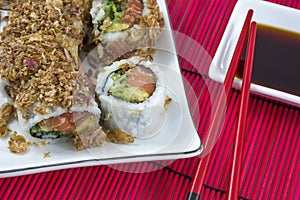 Japanese sushi and soy sauce in white plates with red chopsticks