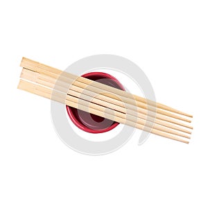 Japanese sushi sticks or chopsticks over red sauce bowl isolated on white background. Top view