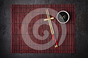 Japanese table setting. Bamboo chopsticks and soy sauce bowl on striped mat