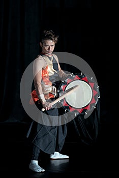 Japanese Taiko drummer hits the drum on stage