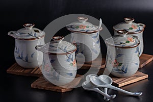 Japanese teacup set with floral pattern and wooden saucer on black background