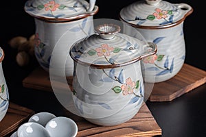 Japanese teacup set with floral pattern and wooden saucer on black background