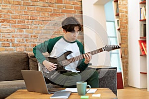 Japanese Teenager Boy Mastering Electric Guitar Chords Using Computer Indoor