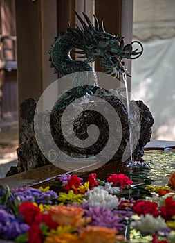 Japanese temple water fountain with a bronze dragon sculpture.