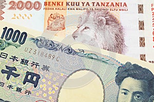 A Japanese thousand yen note paired with a orange and white 2000 shilling bill from Tanzania.