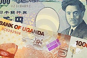 A Japanese thousand yen note paired with a orange and white one thousand shilling bill from Uganda.