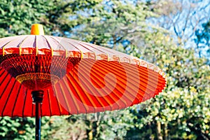 Japanese traditional red umbrella or parasol with green trees