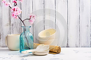 Japanese utensils, dinnerware, chopsticks and branch of blooming sakura on white asian background