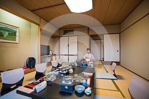 A Japanese waitress in kimono preparing the Kaiseki cuisine