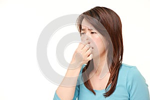 Japanese woman holding her nose because of a bad smell