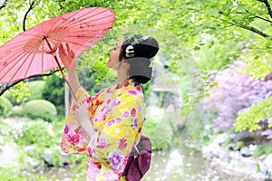 Traditional Asian Japanese beautiful Geisha woman wears kimono bride with a red umbrella in a graden photo