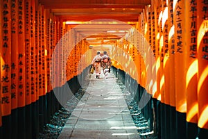 Japanese woman in kimono dress among red wooden Tori Gate at Fushimi Inari Shrine in Kyoto, Japan