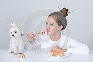 Japanese woman sushi style. Eating japanese sushi set. Beauty young woman and dog eating sushi with a chopsticks