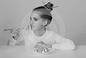 Japanese woman sushi style. Eating japanese sushi set. Beauty young woman eating sushi with a chopsticks, isolated on