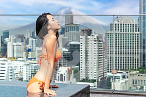Japanese woman travel and relax in hotel rooftop swimming pool