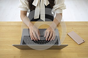 A Japanese woman typing laptop by remote work in the office faceless composition