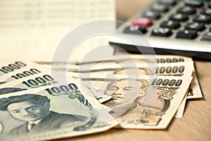 Japanese yen banknote, bank statement book and calculator