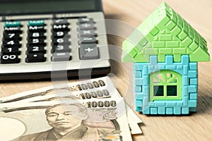 Japanese yen with house model and calculator on wood background