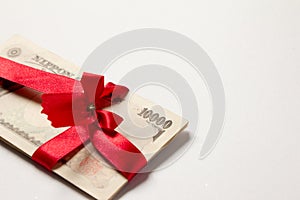 Japanese yen with the red bow on white background