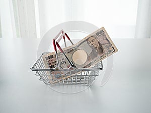 Japanese Yen in shopping basket on white background