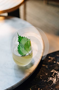 Japanese Yuzu Cocktail with Shiso Leaves Green Perilla in glass on marble top table