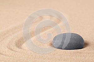 Japanese zen meditation garden with a round stone on sandy background with copy space