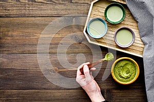 Japanise tea ceremony with matcha tea. Bowl with powder and cups with beverage on tablecloth on dark wooden background