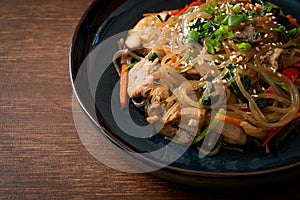 Japchae or stir-fried Korean vermicelli noodles with vegetables and pork topped with white sesame