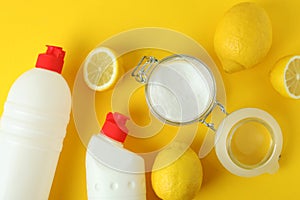 Jar of acid powder, lemons and detergents on yellow background