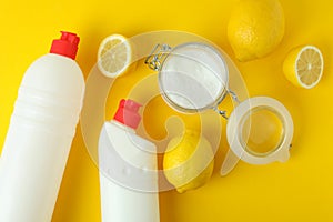 Jar of acid powder, lemons and detergents on yellow background