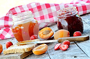 Jar of apricot and strawberry jam, fresh apricots and strawberries